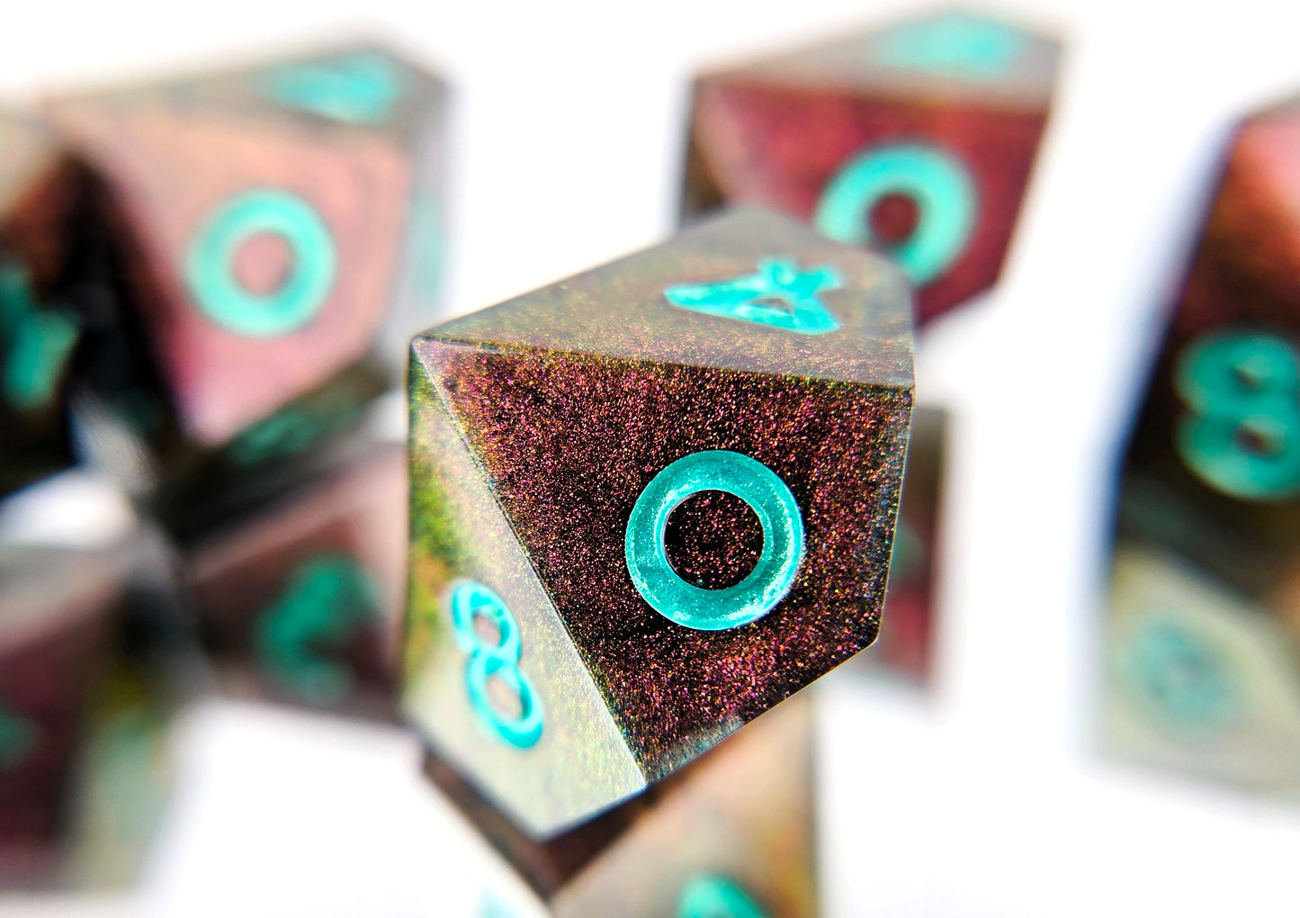 A closeup of a d10 from a d10 ttrpg dice set. The dice are a red/purple/yellow/green colorshift shimmer with metallic cool green numbering.