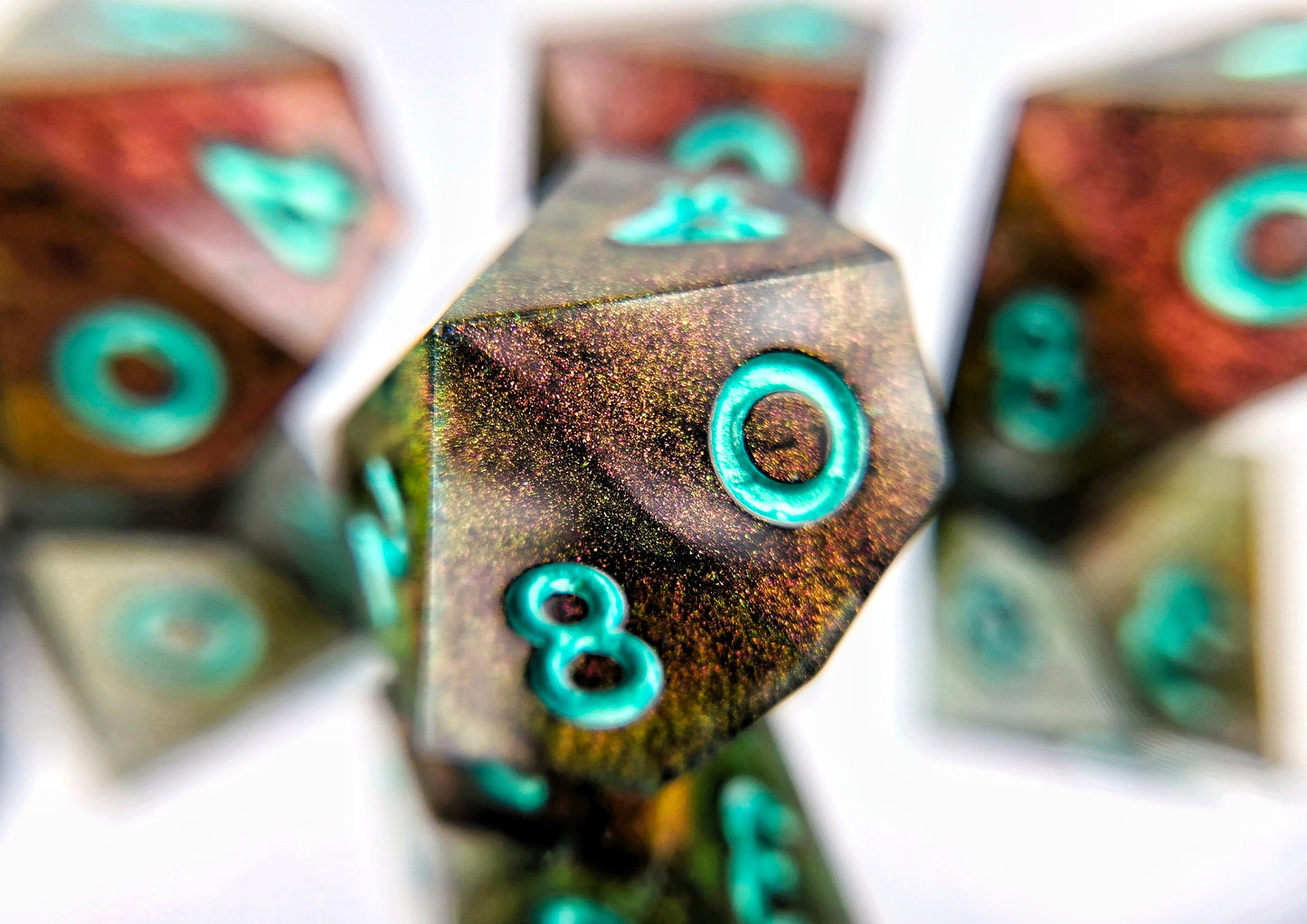 A closeup of a d10 from a d10 ttrpg dice set. The dice are a red/purple/yellow/green colorshift shimmer with metallic cool green numbering.
