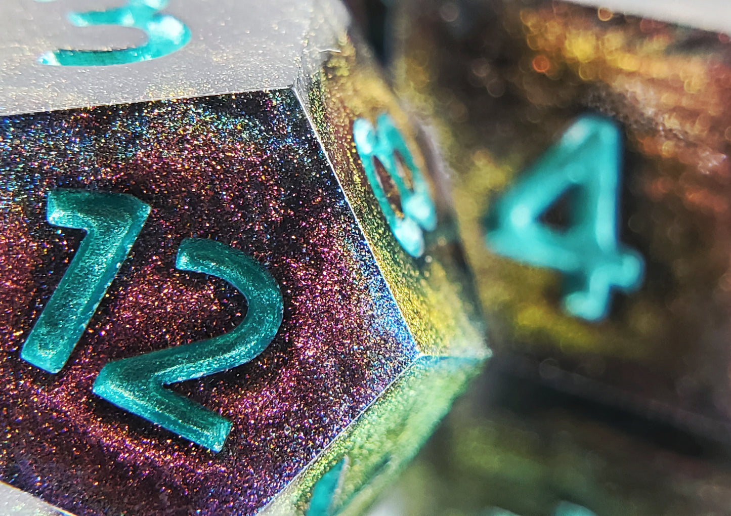 A closeup of a d12 from a ttrpg dice set. The dice are a red/purple/yellow/green colorshift shimmer with metallic cool green numbering.