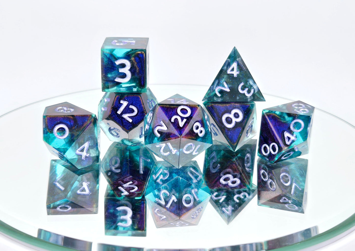 A 7 piece polyhedral ttrpg dice set. The dice are transparent light blue with ultrafine glitter sparkles, colorshift bloops, and light purple metallic numbers.