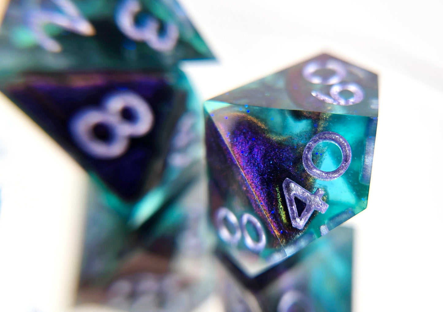 A closeup of a d% from a ttrpg dice set. The dice are transparent light blue with ultrafine glitter sparkles, colorshift bloops, and light purple metallic numbers.