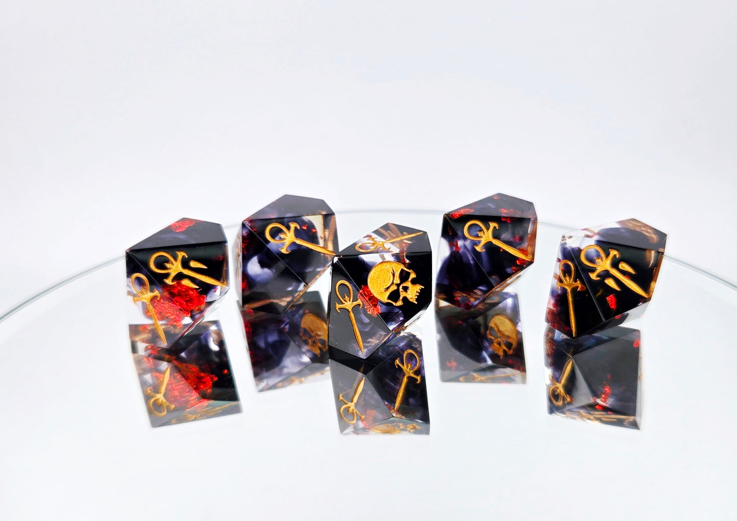 A Vampire the Masquerade Hunger style 5d10 set. The dice are clear with black ink and red foil swirled within. The symbols are inked in gold.