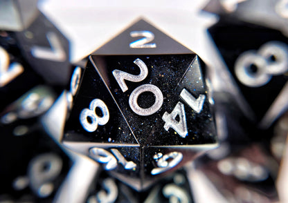 A closeup of a d20 from a ttrpg dice set. The dice are a swirl of plain black and shimmery black with bright silver numbers.