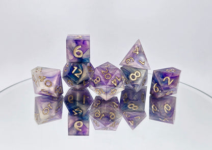 A 7 piece polyhedral ttrpg dice set. The dice are a warm pearlescent base with purple and navy ink swirled over top with soft gold numbers.