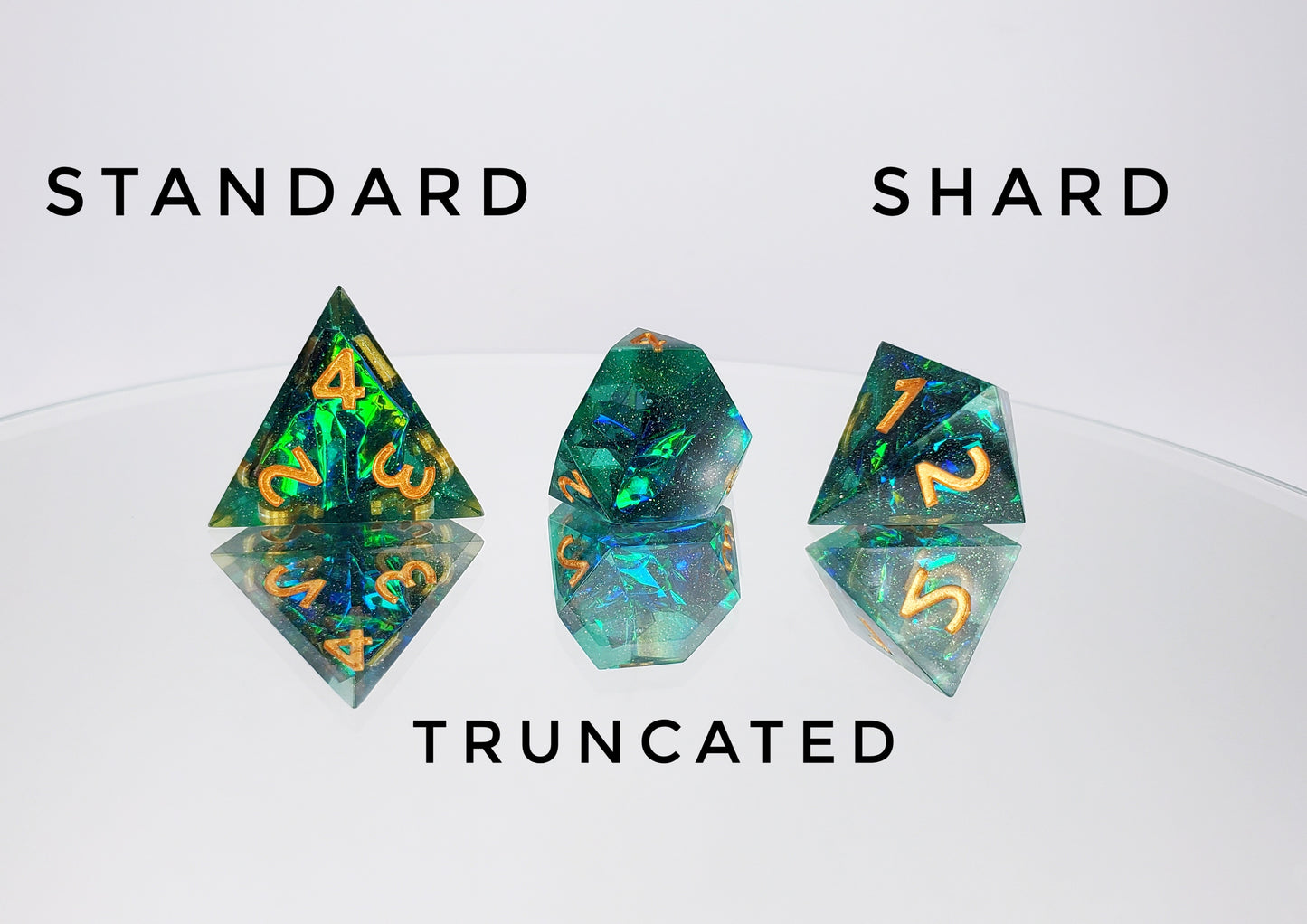 A comparison of a standard caltrop d4, a truncated d4, and a shard d4. The dice are a transparent green with reflective mylar embedded inside with super fine green glitter throughout and golden numbers.