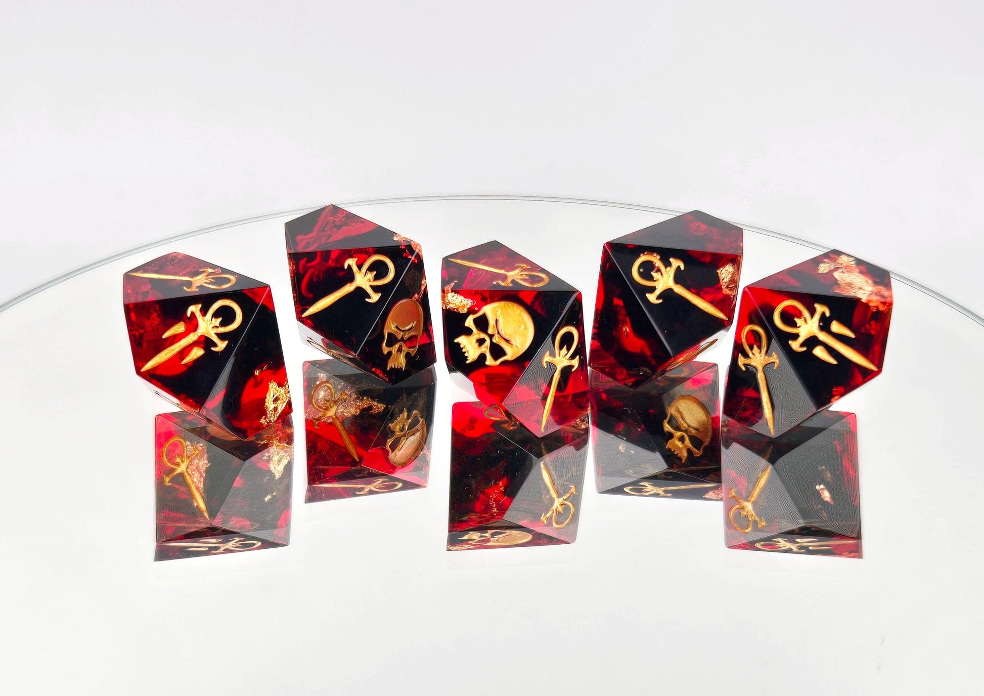 A set of 5 Vampire the Masquerade Hunger style dice. The dice are transparent red with black ink and gold foil inside. The symbols are inked in gold.