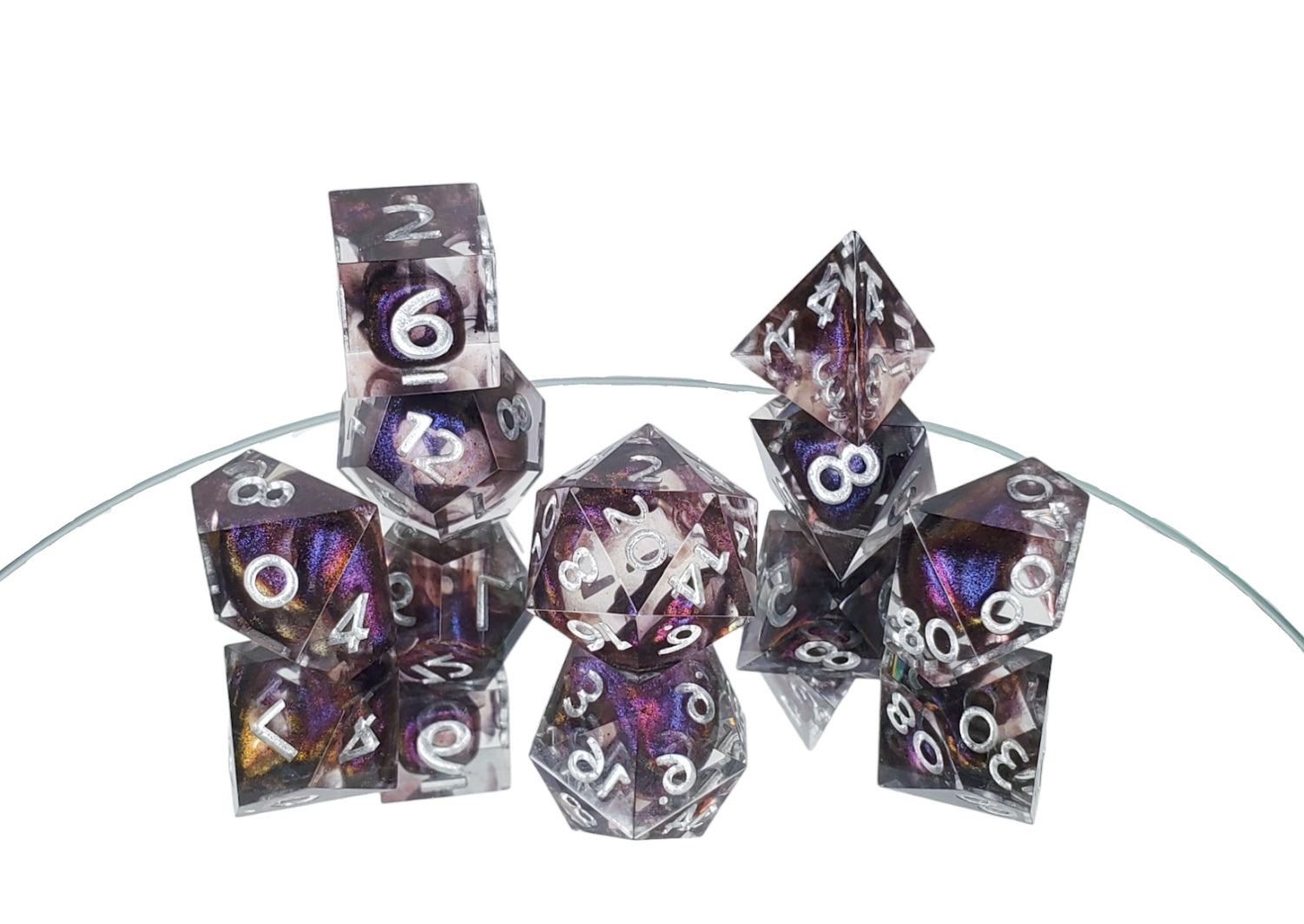 Polyhedral dice set of clear resin with dark purple colorshifting shimmer bloops and silver numbering.