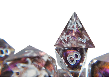 Closeup of the caltrop style d4 on the dice set of clear resin with dark purple colorshifting shimmer bloops and silver numbering.