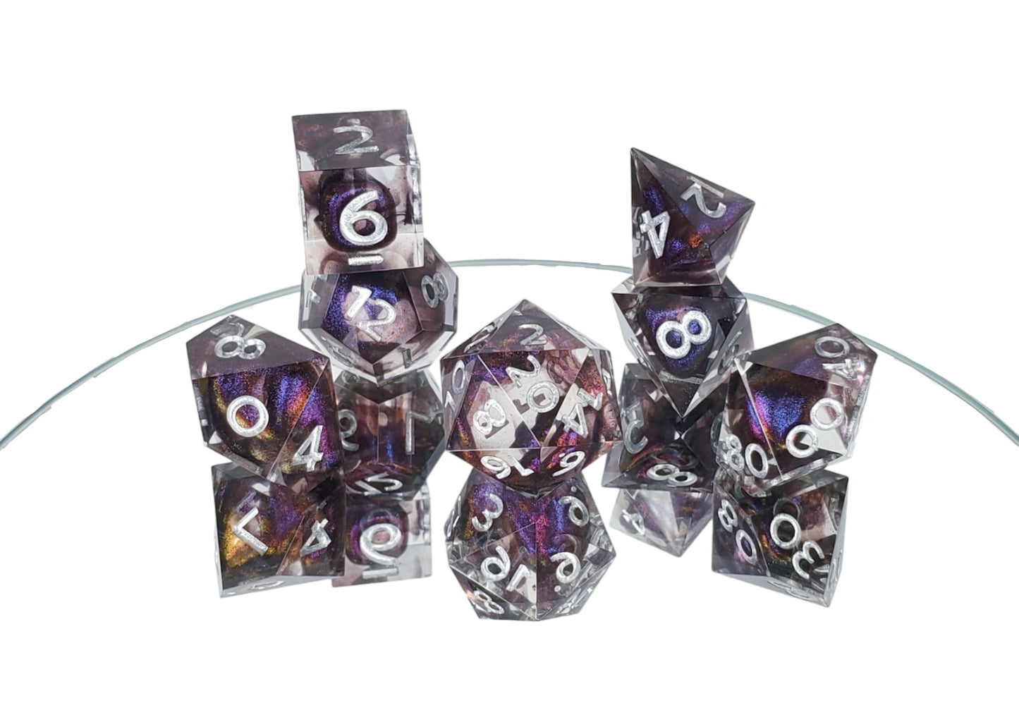 Polyhedral dice set with an alternate d4 shape of clear resin with dark purple colorshifting shimmer bloops and silver numbering.