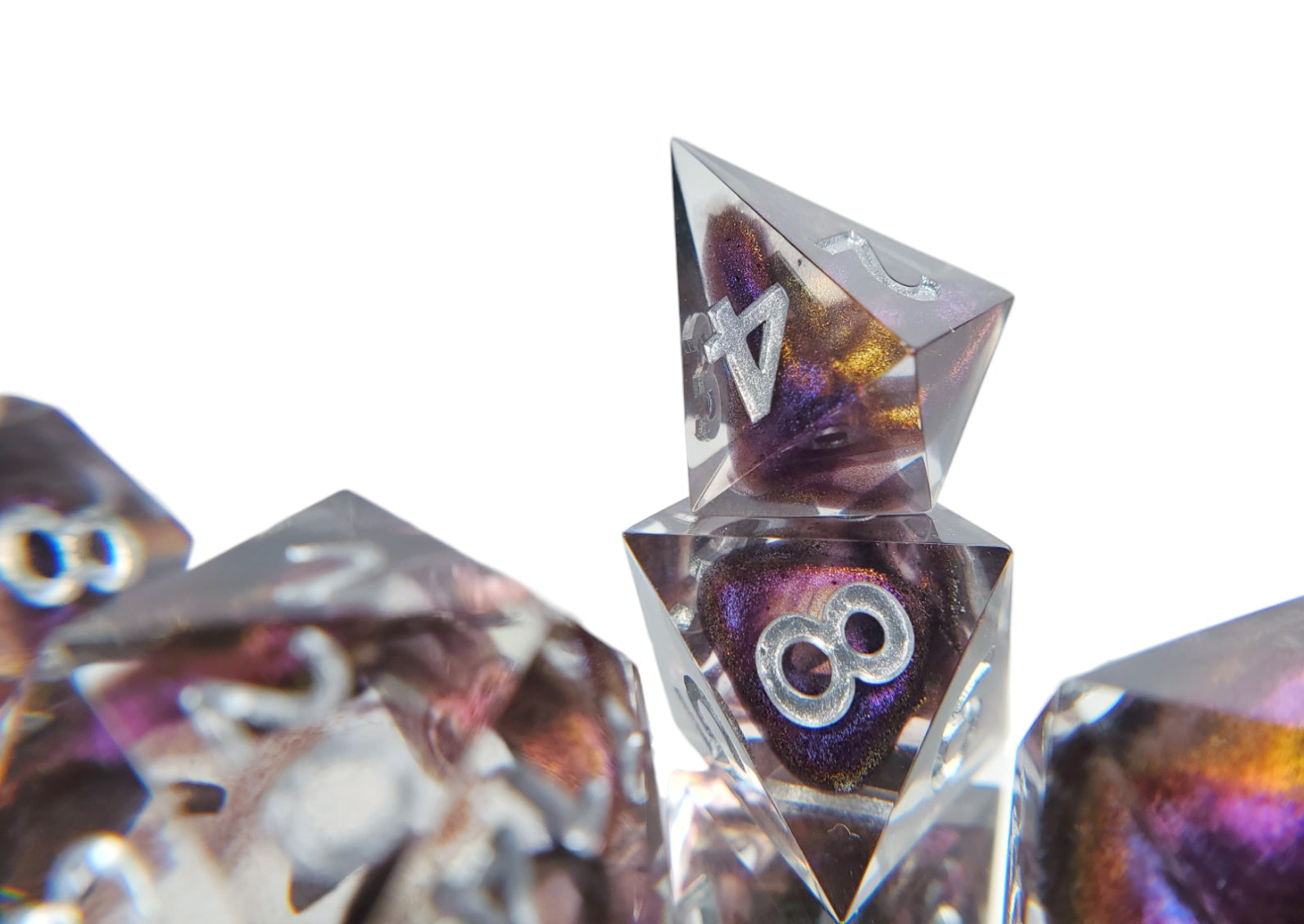 Closeup of the shard style d4 on the dice set of clear resin with dark purple colorshifting shimmer bloops and silver numbering.