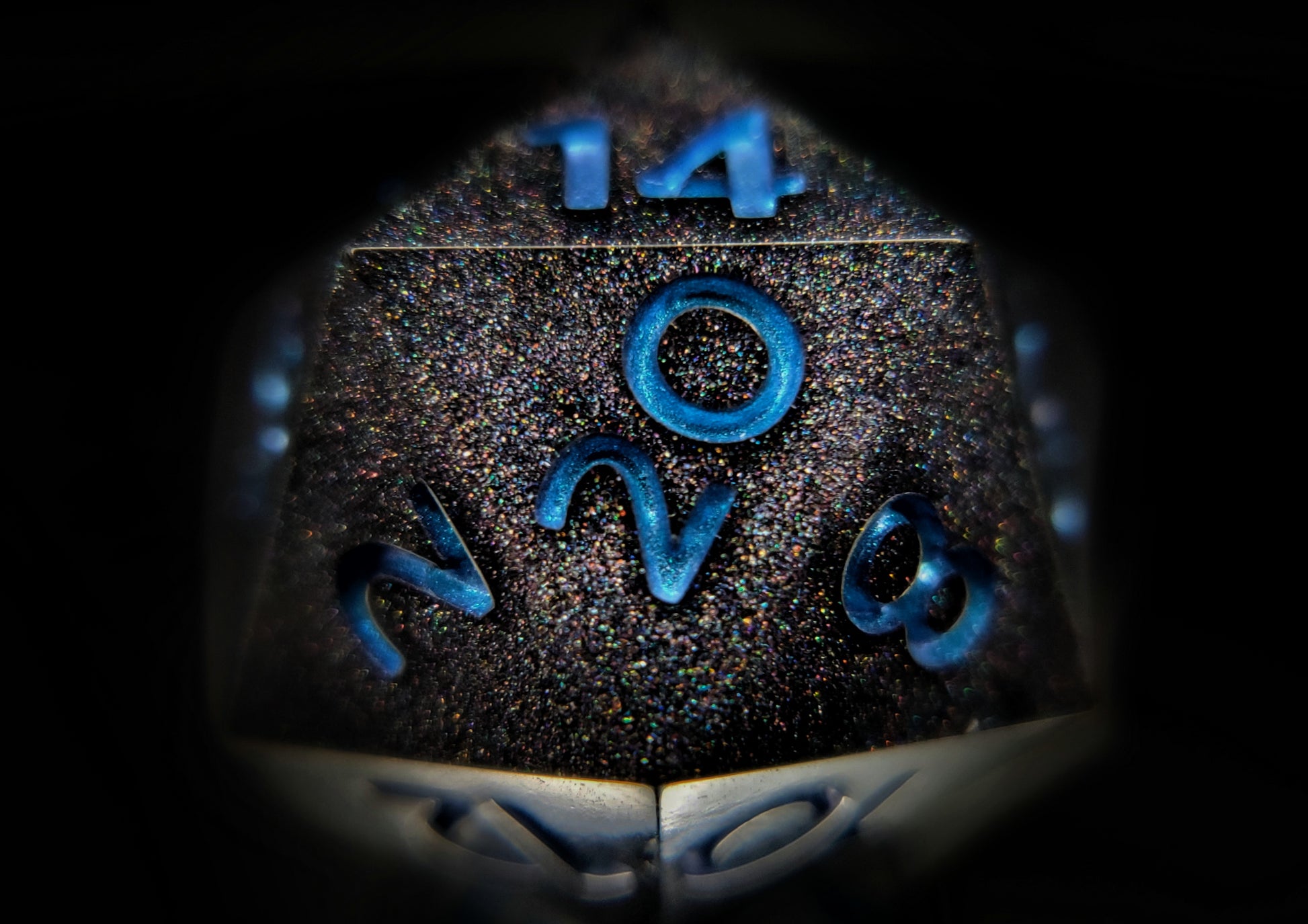 A closeup of a d20 from a ttrpg dice set. The die is packed with fine rainbow holographic glitter and bright blue numbers with a mild colorshift to purple visible at the edges of some numbers.