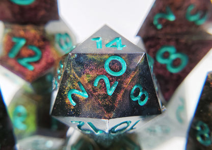 A closeup of a d20 from a ttrpg dice set. The dice are a red/purple/yellow/green colorshift shimmer with metallic cool green numbering. 