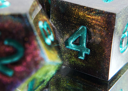 A closeup of a d6 from a ttrpg dice set. The dice are a red/purple/yellow/green colorshift shimmer with metallic cool green numbering. 